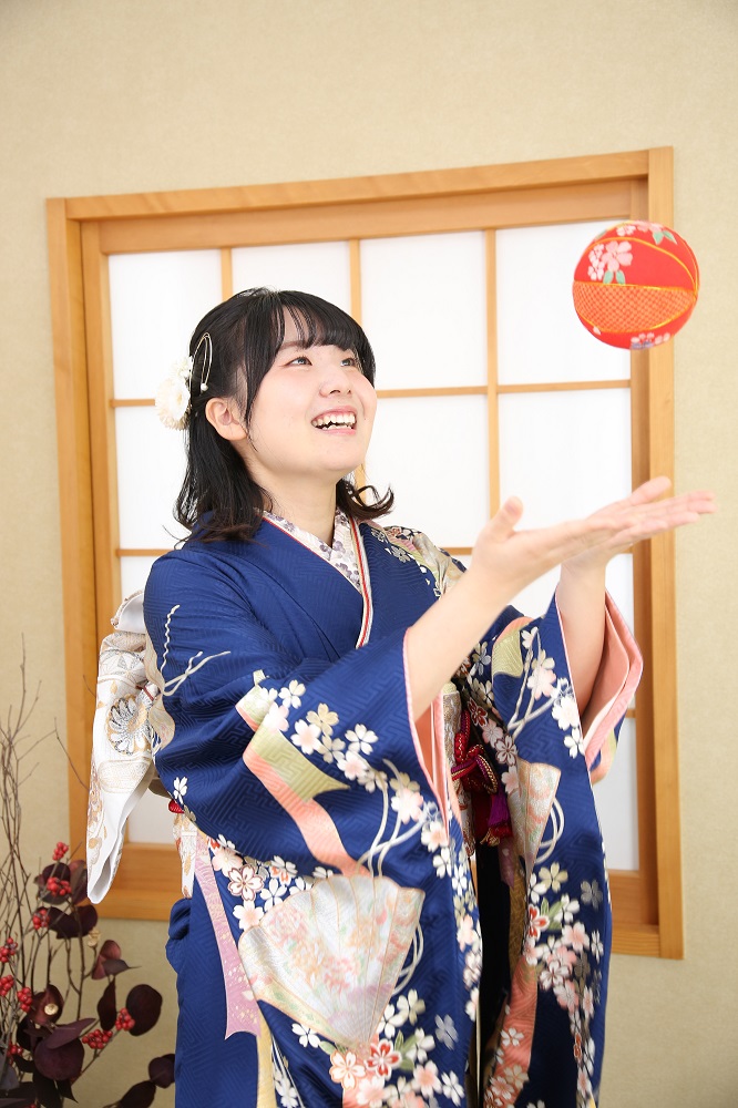 振袖前撮り撮影会で紺地の振袖を着て鞠を投げているポーズの女性